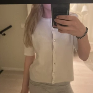 Vit kofta från 157 - FINNS EN EXTRA KNAPP TILL. Säljer en söt vit kofta från 157 i storlek XS. Koftan har pärlknappar och en mjuk, stickad känsla. Perfekt för en stilren look. Passar bra till både jeans och kjol. 🌟