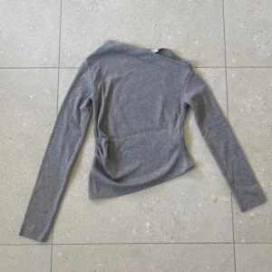 Grå långärmad tröja från Zara - Säljer en denna super snygga asymmetriska/ off shoulder tröjan från Zara i storlek M, dock kanske liten i storleken💓❕Aldrig använd❕