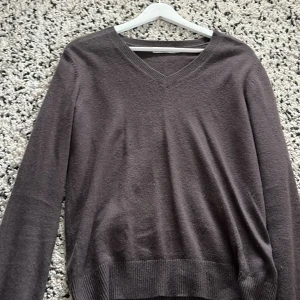 Brun kashmirtröja från Lochmere - Mjuk och lyxig brun kashmirtröja från Lochmere med v-ringning och långa ärmar. Perfekt för dig som gillar klassisk stil med en chill vibe. Ribbstickade muddar vid ärmslut och nederkant ger en snygg finish.