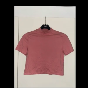 Rosa croppad polotopp från H&M Divided - Säljer en rosa croppad polotopp från H&M Divided. Toppen har korta ärmar och en högre krage som ger en clean och trendig look. 