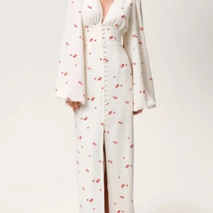 Adoore POSITANO DRESS - Säljer ännu en till adoore åt en kompis. Superfin långklänning i vit med små röda blommor, djup v-ringning och långa vida ärmar. Knappar framtill och slits nertill ger en snygg och trendig look. Perfekt för sommarens alla tillfällen!