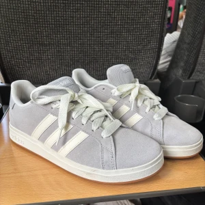 Adidas Grand court base 00’s - Snygga grå sneakers från adidas i modellen Grand court base 00’s i storlek 39 och 1/3. De är endast använda en dag utomhus men storleken passar inte och kan inte skicka tillbaka då jag gått ute med dom. Köpta för 800kr