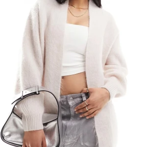 Ljusbeige oversized stickad kofta other stories - Supermjuk och oversized kofta i ljusbeige ton. Koftan är stickad med breda ribbade muddar och har en öppen front utan knappar. Perfekt för lager-på-lager och chill vibes. Passar dig som gillar en relaxed och cozy stil.