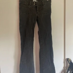 Svarta bootcut jeans från 157 - Snygga svarta jeans från 157 med bootcut passform och raka ben. Jeansen har två stora fickor fram, dubbla knappar i midjan och är tillverkade i klassiskt denimtyg. Perfekta för en avslappnad och trendig look.