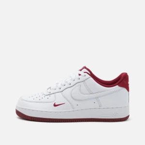 Nike Air Force 1 vit/röd sneakers - Nike Air Force 1 sneakers i vitt skinn med röda detaljer och röd sula. Klassisk låg modell med perforerad tå, vit swoosh och röd insida. Ikonisk streetstil med snörning och platt sula – perfekt för dig som vill sticka ut med en clean look. Storlek 38, endast använd 2ggr - men de passar tyvärr inte min fot. 