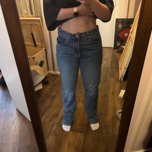 Levi's 501 blå jeans straight fit - Klassiska blå Levi's 501 jeans med rak passform och hög midja. Jeansen är i denim med fem fickor och knappgylf. Perfekta för en avslappnad och tidlös stil. Snygga att styla med både sneakers och boots. (Storlek W32 L32)