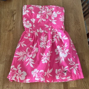 Rosa blommig tubklänning Hollister - En kort klänning från hollister, köpt från Sellpy. Plagget är i bra skick. Säljer klänningen för det inte satt så bra på mig.