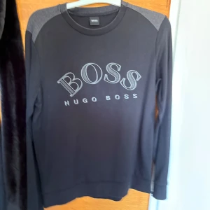 Svart långärmad tröja Hugo Boss - Svart långärmad tröja från Hugo Boss med grå axelpartier och grå BOSS-logga framtill. Köpte den i johnells för några års sen.                                     Pris kan diskuteras 