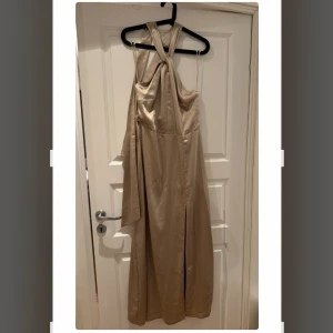 Klänning  - Långklänning från Lovisa Barkmans kollektion med Bikbok. Klänningen har halterneck med långa knytsnlren och en slits framtill samt är låg i ryggen. Helt ny med prislappen kvar. Storlek 44.