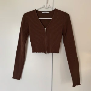 Brun topp med dragkedja - Brun ribbad croppad topp med dragkedja från NA-KD. 