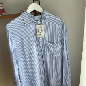 Blåvit randig linneskjorta från H&M - Snygg blåvit randig skjorta från H&M i linnemix. Aldrig använd.