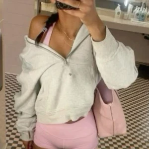 Lululemon scuba - Säljer en ljusgrå croppad hoodie med half zip och oversized passform. Tröjan har långa ärmar och är perfekt för en chill och sportig look. Passar grymt till träning eller när du vill vara bekväm men ändå snygg.