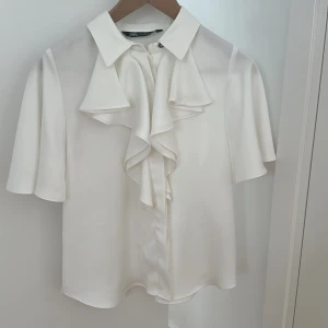 Topp - Säljer denna superfina helt oanvända vita sidensommartoppen i storlek S.Man knäpper den med knappar och den har en liten fin guld detalj vid kragen. Köpt utomlands, går inte att köpa i Sverige. Pris kan diskuteras!❤️