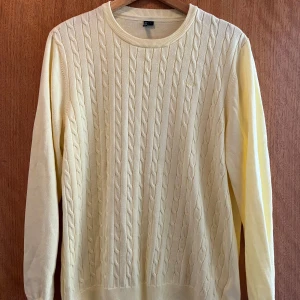 Gul kabelstickad tröja Hampton Republic - Ljusgul kabelstickad tröja från Hampton Republic i storlek L. Tröjan har rund halsringning, ribbade muddar och ett diskret broderat logomärke på bröstet. Perfekt för dig som gillar klassisk och stilren look.