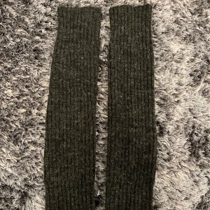 Mörkgråa ribbade stickade benvärmare  - Säljer ett par långa, mörkgråa stickade strumpor med ribbad struktur. Tjockt, mjukt och varmt material som känns riktigt cozy under kyliga dagar. Använda en gång. 🤍
