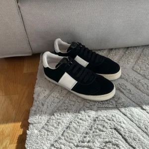 Valentino Garavani flycrews svart vita. - Svarta och vita Valentino Garavani Rockrunner sneakers med bred vit läderdetalj på sidan, svarta mockadetaljer och klassiska nitar baktill på sulan. Skorna har svart snörning, rund tå och vit sula. Perfekt för dig som vill ha en lyxig och edgy look.