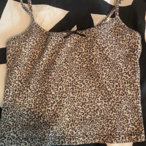 Leopardmönstrad linnetopp från Primark - Säljer en snygg leopardmönstrad linnetopp från Primark i storlek XS. Toppen har tunna axelband och en liten rosett framtill. Perfekt för dig som gillar djurmönster och vill sticka ut lite extra. Färgerna går i beige och svart.