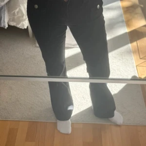 Svarta bootcut byxor  - Svarta bootcut byxor från H&M Divided i storlek 34. Byxorna har låg midja, raka ben med utsvängd nederdel och snygga fickdetaljer framtill. Materialet är en mix av bomull och polyester med lite stretch för skön passform.