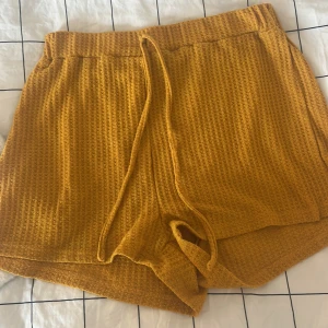 Gula stickade shorts från SHEIN - Mysiga gula stickade shorts från SHEIN i storlek L. De har en loose passform, hög midja och snörning i midjan. Materialet är ribbat och mjukt, perfekt för chill dagar. Snygg struktur och skön känsla mot huden.