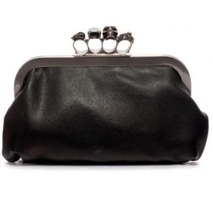 Clutch med ringar - Cool svart kuvertväska i skinn med silverfärgad metallram och ikoniska dödskalle-detaljer på knoghandtaget. Väskan har en mjuk, slät yta och ett statement-lås med svarta stenar och unika ringar. Går att lägga till kedja är dock inget som tillkommer