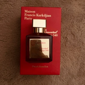 Baccarat Rouge 540 Eau de Parfum - Exklusiv parfym från Maison Francis Kurkdjian, Baccarat Rouge 540. Flaskan är djup röd med en elegant guldig etikett och lock. Kommer i en lyxig röd förpackning med guldtext. En ikonisk doft som utstrålar lyx och elegans.