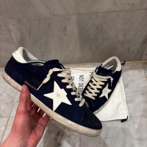 Mörkblå Golden Goose - Säljer ett par mörkblå sneakers från Golden Goose med vit stjärna på sidan och vita skosnören. Bara använda några få gånger. Endast dustbag tillkommer. Skick 8,5/10, bedöm själv. Nypris ca: 7000kr, Mitt pris 3499kr. Storlek 46,  men skulle säga att det passar 45 också. Priset är inte hugget i sten! Fråga på! Skickar inom 24 timmar! ‼️KVITTO FINNS‼️