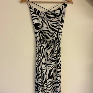 Zebramönstrad långklänning från SHEIN - Säljer en långklänning från SHEIN med svartvitt zebramönster. Klänningen har smala axelband, snörning i ryggen och är figurnära. Perfekt för dig som vill sticka ut med ett djurmönster!