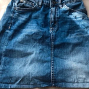 Jeanskjol från Crocker - Säljer en klassisk blå jeanskjol från Crocker med femficksmodell och knapp- samt dragkedjestängning framtill. Kjolen har normal passform och är tillverkad i slitstarkt jeanstyg. Perfekt till vardags för en avslappnad look.