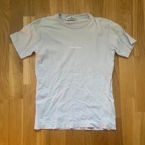 Lila t-shirt från Stone Island Kids - Säljer en lila t-shirt från Stone Island med tryckt logga på bröstet och ett större grafiskt tryck på ryggen. Klassisk passform och rund halsringning. Perfekt för dig som gillar stilrena plagg med diskreta detaljer. Passar bäst på barn mellan 11-12