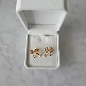 Rosettörhängen - Säljer ett par söta örhängen i form av rosetter.