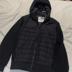 Svart Cardigan från ZARA - Svart cardigan från ZARA med dragkedja. Jackan har huva, långa ärmar och ribbade muddar. Perfekt för lager-på-lager och enkel att matcha med det mesta.