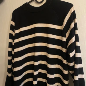 Svart och vit randig stickad tröja från Object - Säljer en svart och vit stickad tröja från Object i storlek XS. Tröjan har ett klassiskt randigt mönster, rund halsringning och långa ärmar. Perfekt för en avslappnad och stilren look. Den passar även upp i större storlekar då den är lite längre och har ett stretchigt material 