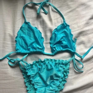 Turkos bikini från Calzedonia - Snygg turkos bikini från Calzedonia med volangdetaljer och knyt i både överdel och underdel. Klassisk trekantsmodell på toppen, perfekt för strand och pool!
