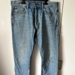 Ljusblå jeansbyxor från Weekday - Klassiska ljusblå jeans från Weekday med fem fickor och knappgylf. Byxorna har raka ben och normal passform, perfekt för en avslappnad stil. 