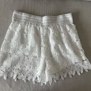 Vita spets-shorts med blommigt mönster - Superfina vita virkade  shorts med bred resår i midjan och detaljerad spets med blommigt mönster🤍🤍 Jag säljer flera liknande på min profil. Storlek S/M