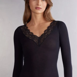 Svart långärmad topp med spets - Säljer en super fin intimissimi tröja i bra skick! Perfekt att styla till olika outfits och ger en elegant touch med spetsen framtill. Pris kan diskuteras