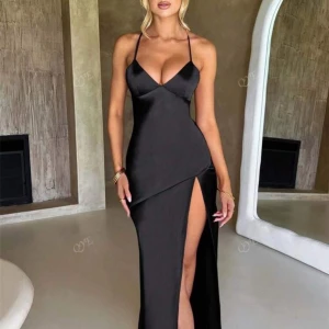 Svart långklänning med slits och öppen rygg - Elegant svart långklänning i satin med smala axelband, hög slits framtill och öppen rygg med snörningsdetalj. Klänningen har en figurnära passform och en stilren, minimalistisk design som ger en lyxig känsla. Perfekt till balen!💛OBS: Lånade bilder från hemsidan, aldrig använd.