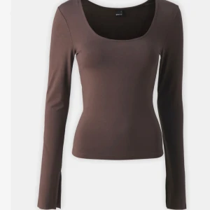Brun långärmad topp med rund hals - Säljer en brun långärmad topp med rund, djup ringning. Toppens material är stretchigt och sitter tight mot kroppen, perfekt att styla till både jeans och kjol. Den är helt ny och har kvar prislappen 