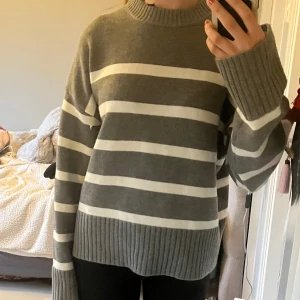 Snygg randig tröja - Mysig stickad tröja från H&M i grått med vita horisontella ränder. Tröjan har lång ärm, ribbad mudd vid ärmslut, nederkant och halsringning. Perfekt för kyligare dagar och enkel att matcha med jeans eller kjol.