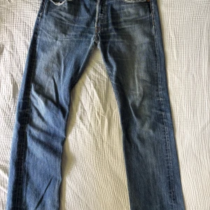 Levi's 501 blå jeansbyxor W32 L34 - Klassiska blå Levi's 501 jeans med raka ben och normal passform. Det är en lagad slitning i skrevet men är inte så märklig när man har på sig dom.