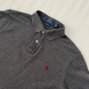 Ralph Lauren Piké - En sjukt snygg Ralph Lauren Polo Piké i perfekt skick✨Skick: Mycket Bra✨ Storlek: S✨ Färg: Mörkgrå med rött märke✨ Vid frågor eller prisförslag så är det bara att kontakta mig😊