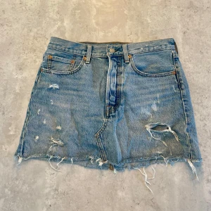 Blå jeanskjol Levi's - Säljer en blå jättefin Levi's jeanskjol från med slitna detaljer. Storlek 27, passar S/M! 💙