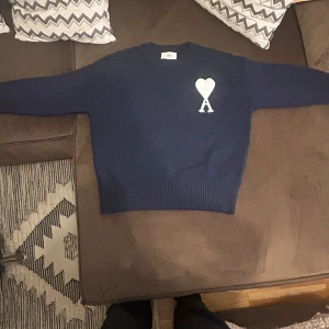 Ami pris tröja - Navy - AMI PARIS – Navy tröja  Säljer en stilren och klassisk stickad tröja från AMI Paris i mörkblått med det ikoniska vita “A heart”-logotypen broderat på bröstet. Tröjan är i toppskick och knappt använd.  ✅ Nära nyskick – inga fläckar, hål eller tvättslitage ✅ Elegant design som passar både vardag och finare tillfällen ✅ 100% äkta ✅ Unisex-passform, passar både herr och dam  Perfekt för dig som gillar fransk design med en modern touch. 📦 Skickas spårbart, Kom med bud pris kan diskuteras!