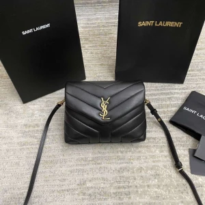 Svart quiltad axelväska från Saint Laurent - Säljer en svart quiltad axelväska från Saint Laurent med ikoniskt YSL-emblem i guld framtill. Väskan är tillverkad i mjukt skinn och har justerbar axelrem samt magnetlås. Snygg och stilren design med lyxig känsla, perfekt för dig som gillar exklusiva accessoarer.