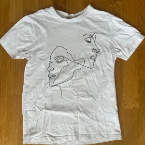 Vit t-shirt - Vit t-shirt från Mister Tee i storlek XS med ett stilrent line art-tryck av två ansikten på framsidan. Klassisk passform med rund hals och korta ärmar. Perfekt för dig som gillar minimalistisk och modern design.