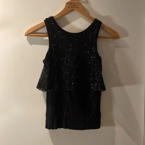Svart paljettopp - Säljer en svart topp men en paljettvolang ovantill. Vet tyvärr inte märke eller storlek men jag tror den är typ xxs-xs
