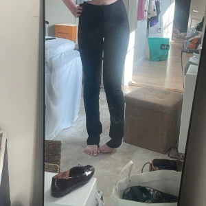Svarta bootcut byxor från Zara - Säljer ett par svarta, högmidjade byxor från Zara med bootcut-snitt. Byxorna har en tight passform upptill och släpper ut vid bensluten. Snygga och stilrena, perfekta till sneakers eller klackar. de har inga defekter bara lite trådar vi knapparna i midjan vilket inte syns när byxorna är på. Man kan öppna den nere med fötterna vid en dragkedja så man kan göra mer bootcut.