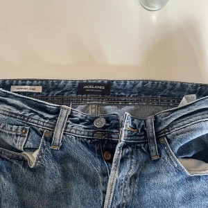 Blå jeans från Jack & Jones - Klassiska blå jeans från Jack & Jones med snygg tvätt och raka ben. Modellen heter Comfort/Mike och har fem fickor, bälteshällor och kontrastsömmar. Perfekta för en avslappnad och stilren look.