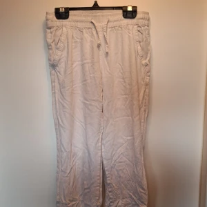 Vita mjukisbyxor från 157 - Vita mjukisbyxor från 157 med resår och snörning i midjan. Byxorna har sidfickor och en bakficka, tillverkade i mjukt bomullstyg. Perfekta för chill dagar eller när du vill ha det extra bekvämt.