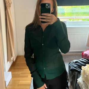 Mörkgrön tunn skjorta  - Snygg mörkgrön skjorta från BikBok i tunn, lätt transparent polyester. Klassisk krage, långa ärmar och knäppning framtill. Perfekt att styla med svarta byxor eller jeans. Säljer då den inte kommer till användning längre 💗💗